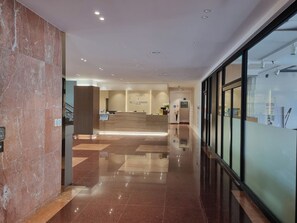 A hotel reception area with a marble floor, a reception desk, and a glass wall on the right. - Ocean Grand Hotel Jeju (Jeju City)