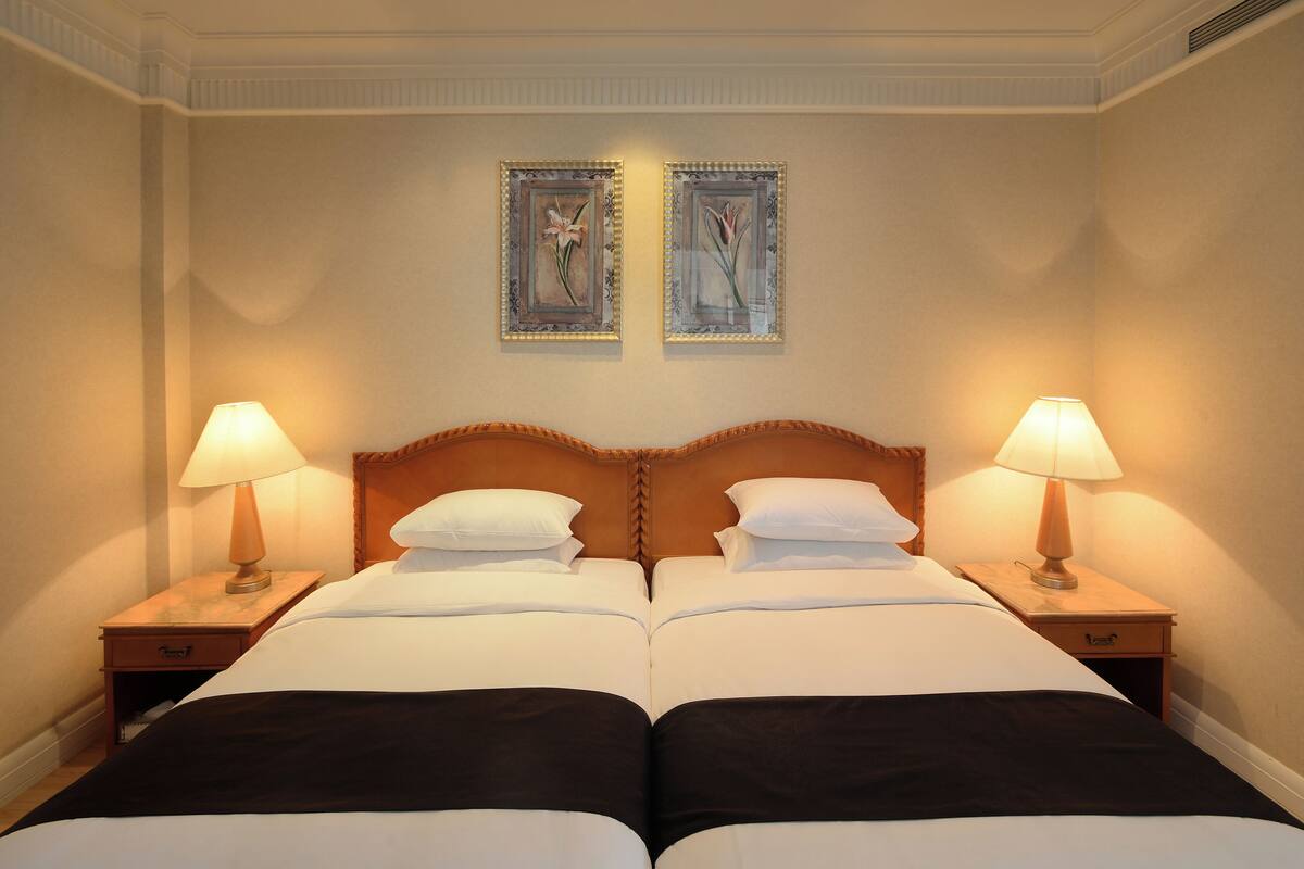 A double bed with two nightstands, each with a lamp, in a hotel room.
