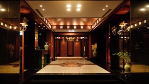 A hotel lobby with a marble floor, wooden paneling, and chandeliers. - Jeju Oriental Hotel & Casino (Jeju City)