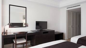Una habitación de hotel con cama, escritorio con silla, televisor y armario.