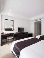 Una habitación de hotel con cama, escritorio con silla, televisor y armario.