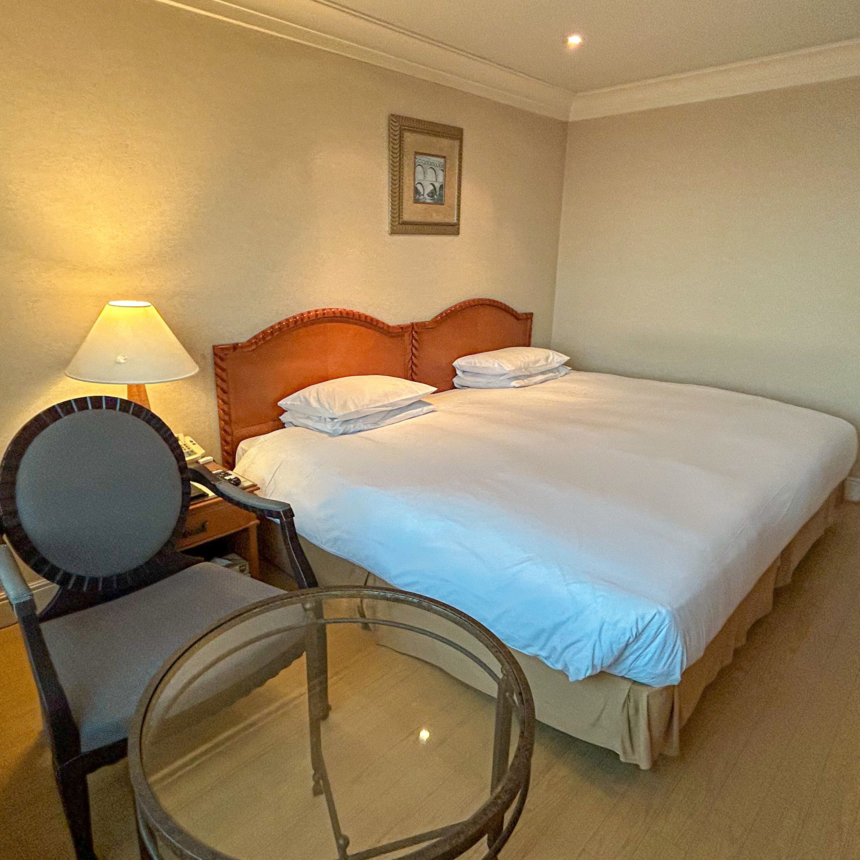 Ein Hotelzimmer mit einem Bett, einem Sessel, einer Lampe und einem Bild an der Wand.