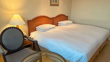 Ein Hotelzimmer mit einem Bett, einem Sessel, einer Lampe und einem Bild an der Wand.