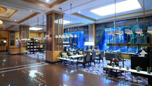 A spacious lobby with a high ceiling, modern chandeliers, and a large seating area with tables and chairs. - Jeju Oriental Hotel & Casino (Jeju City)