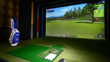 Relax in a room designed for golf enthusiasts, featuring a golf simulation game and a putting mat.