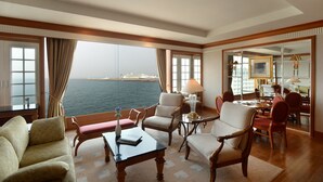 A spacious room with a large window overlooking the sea, furnished with a sofa, armchairs, and a dining area. - Jeju Oriental Hotel & Casino (Jeju City)