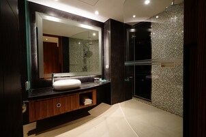 A modern bathroom with a large mirror, a sink, and a shower area.