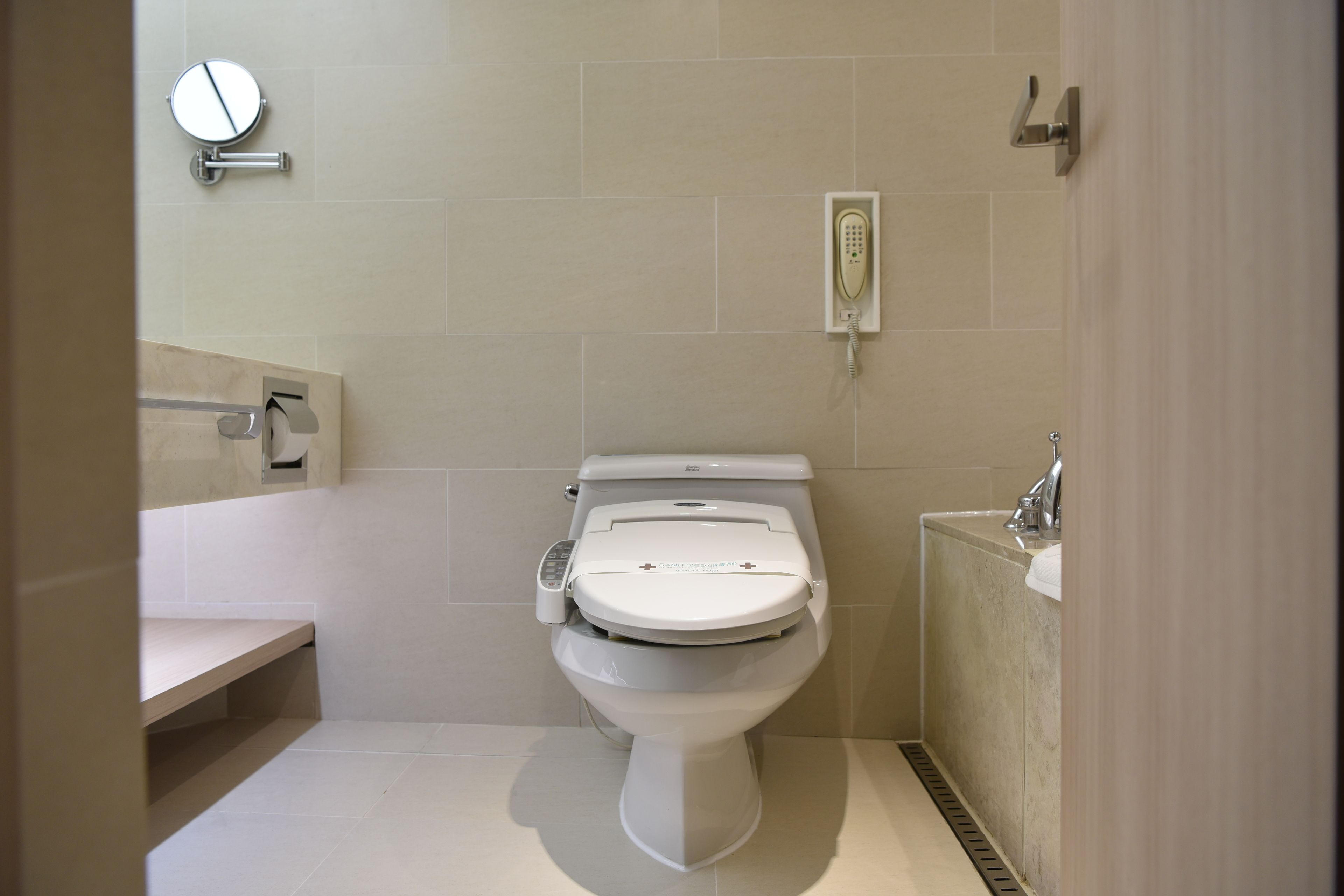Un baño moderno con inodoro, secamanos, espejo y lavamanos.