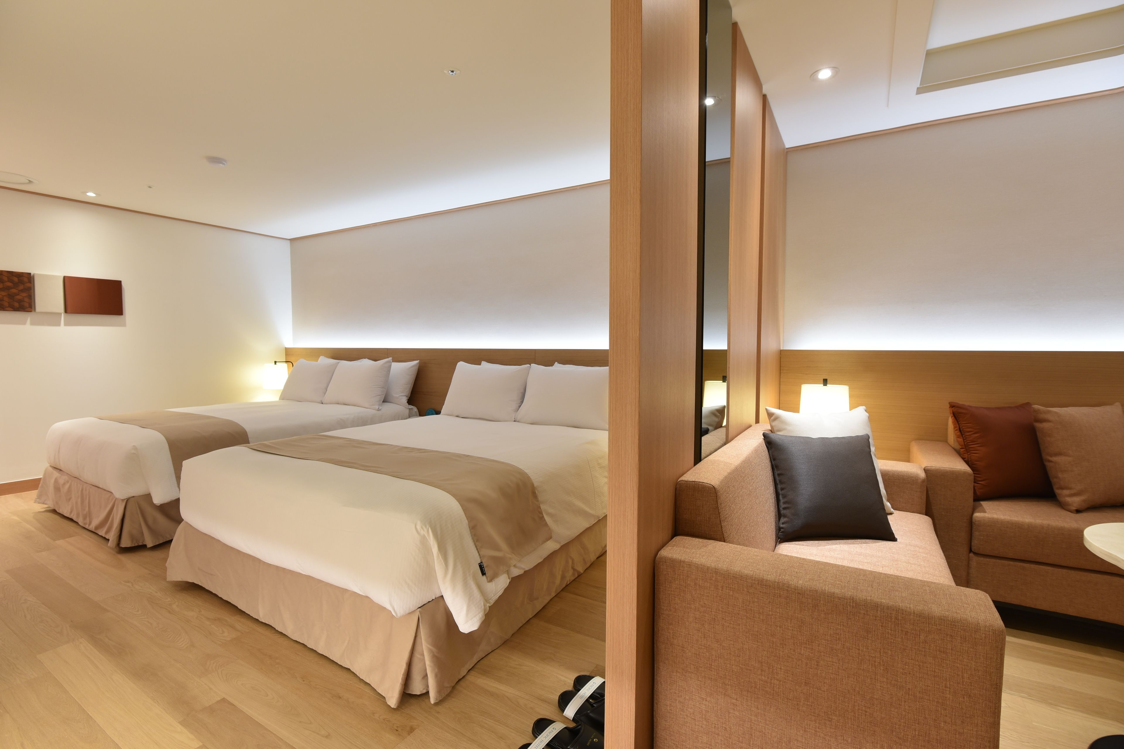 A modern hotel room with a large bed, a sofa, and a small table.