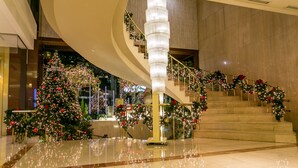 Una imponente escalera con diseño espiral, decorada con guirnaldas y luces festivas, que conduce a un nivel superior.