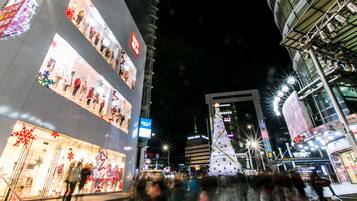 A multi-story building with illuminated storefronts and a large Christmas tree.