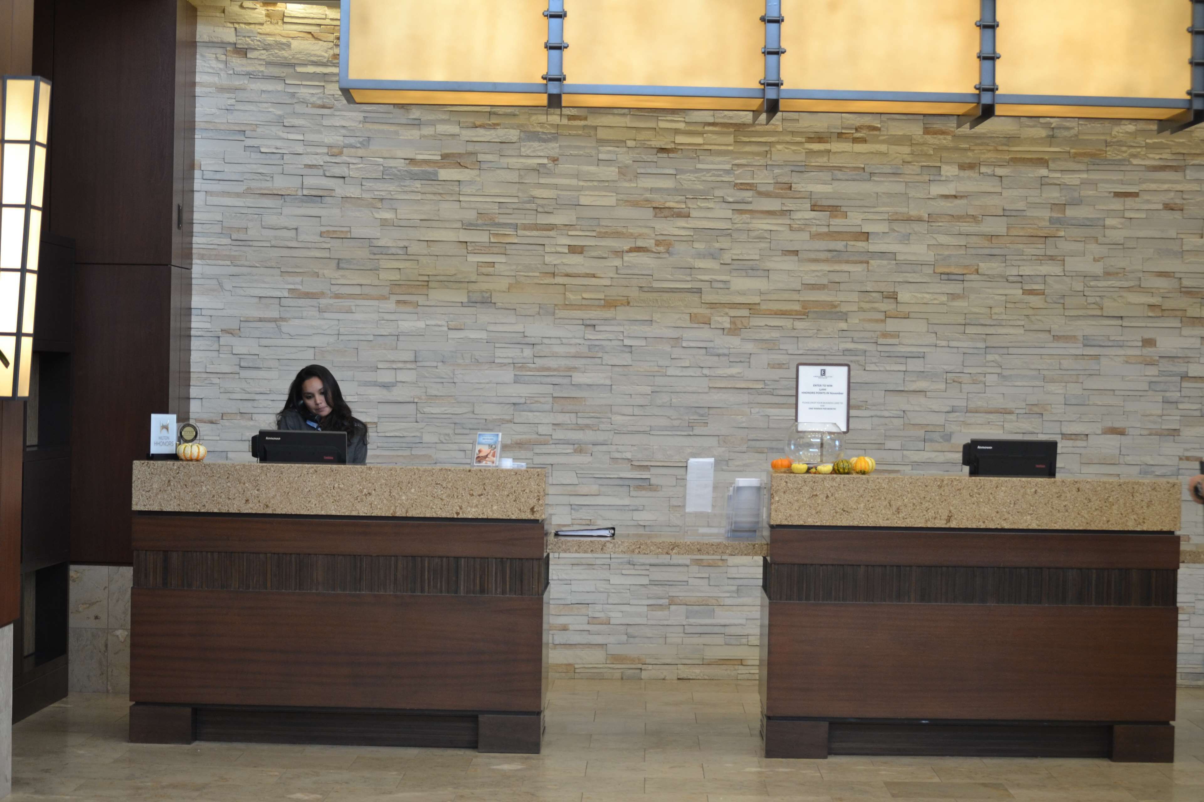 A reception desk with a stone wall backdrop and a wooden counter.