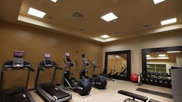 Et fitnesscenter med løbebånd, crosstrainere og vægttræningsudstyr.