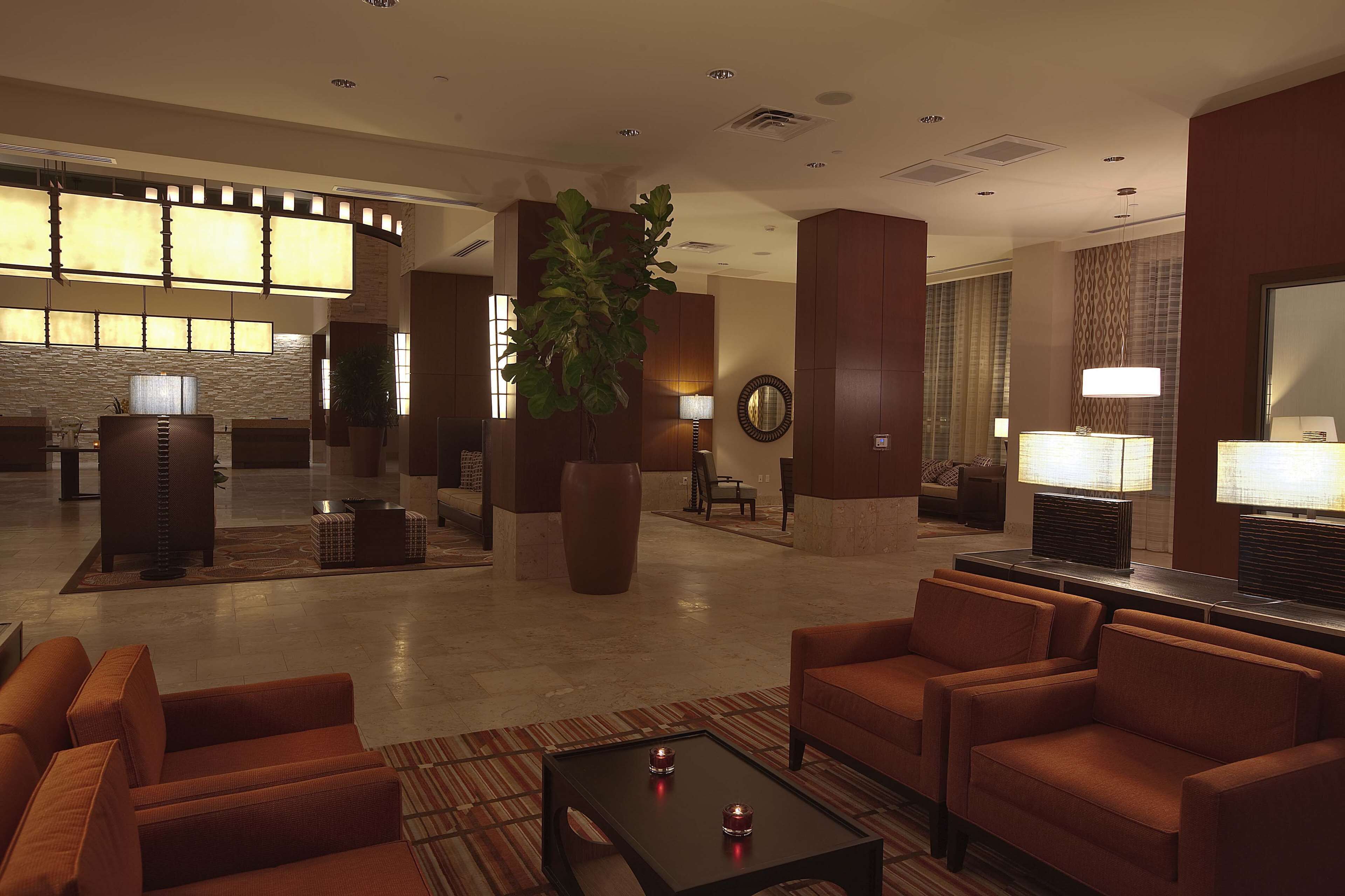 A lobby with sofas, a coffee table, a large plant, and a reception desk.
