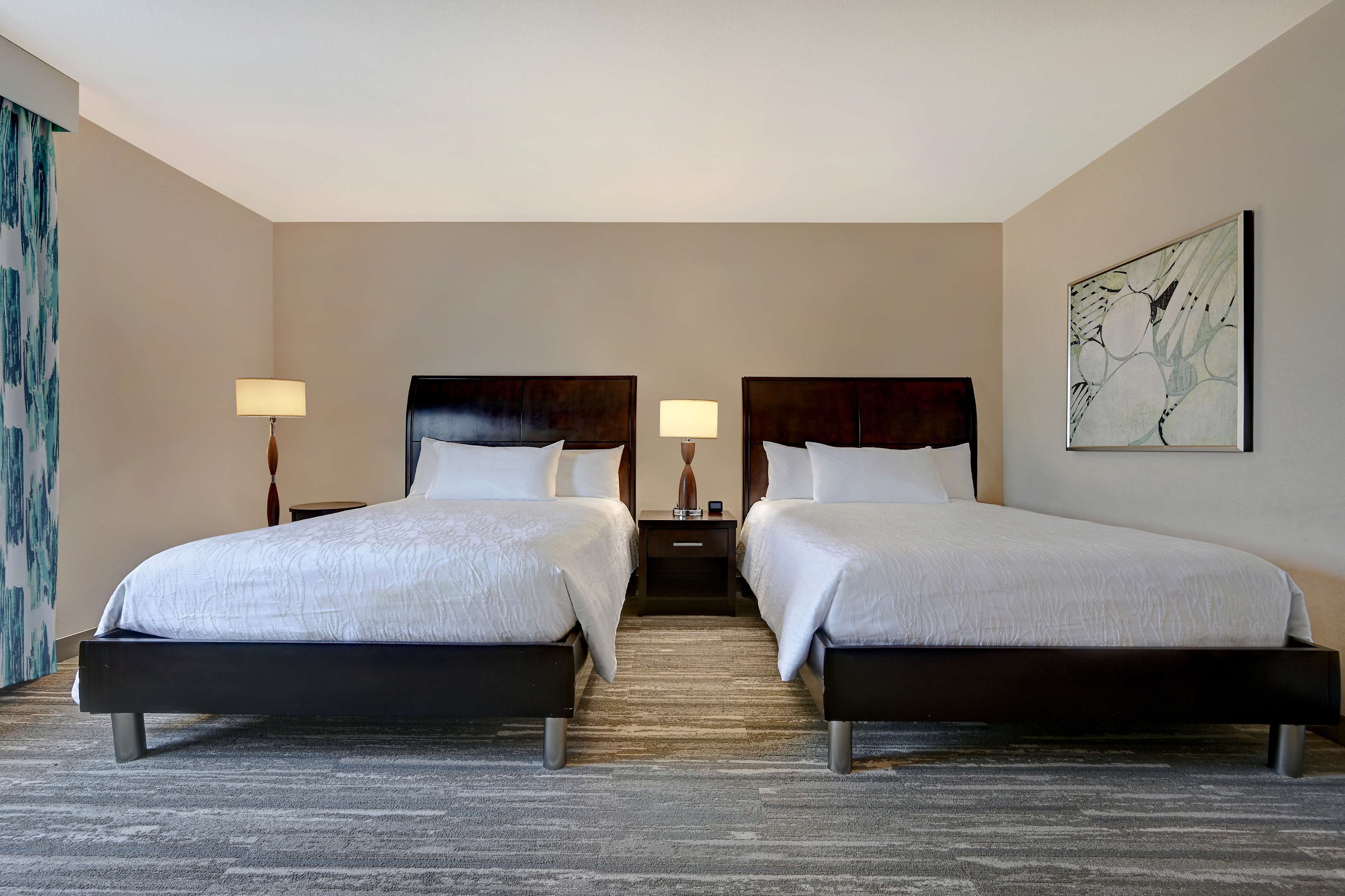 Une chambre d’hôtel avec deux lits, un sol recouvert de moquette et un tableau au mur.