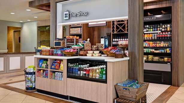 Una tienda llamada 'The Shop' con una variedad de bocadillos, bebidas y productos de alimentación a la vista.