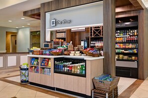 Una tienda llamada 'The Shop' con una variedad de bocadillos, bebidas y productos de alimentación a la vista.
