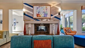 Un vestíbulo moderno con sofás turquesa, una chimenea y un cuadro abstracto grande.