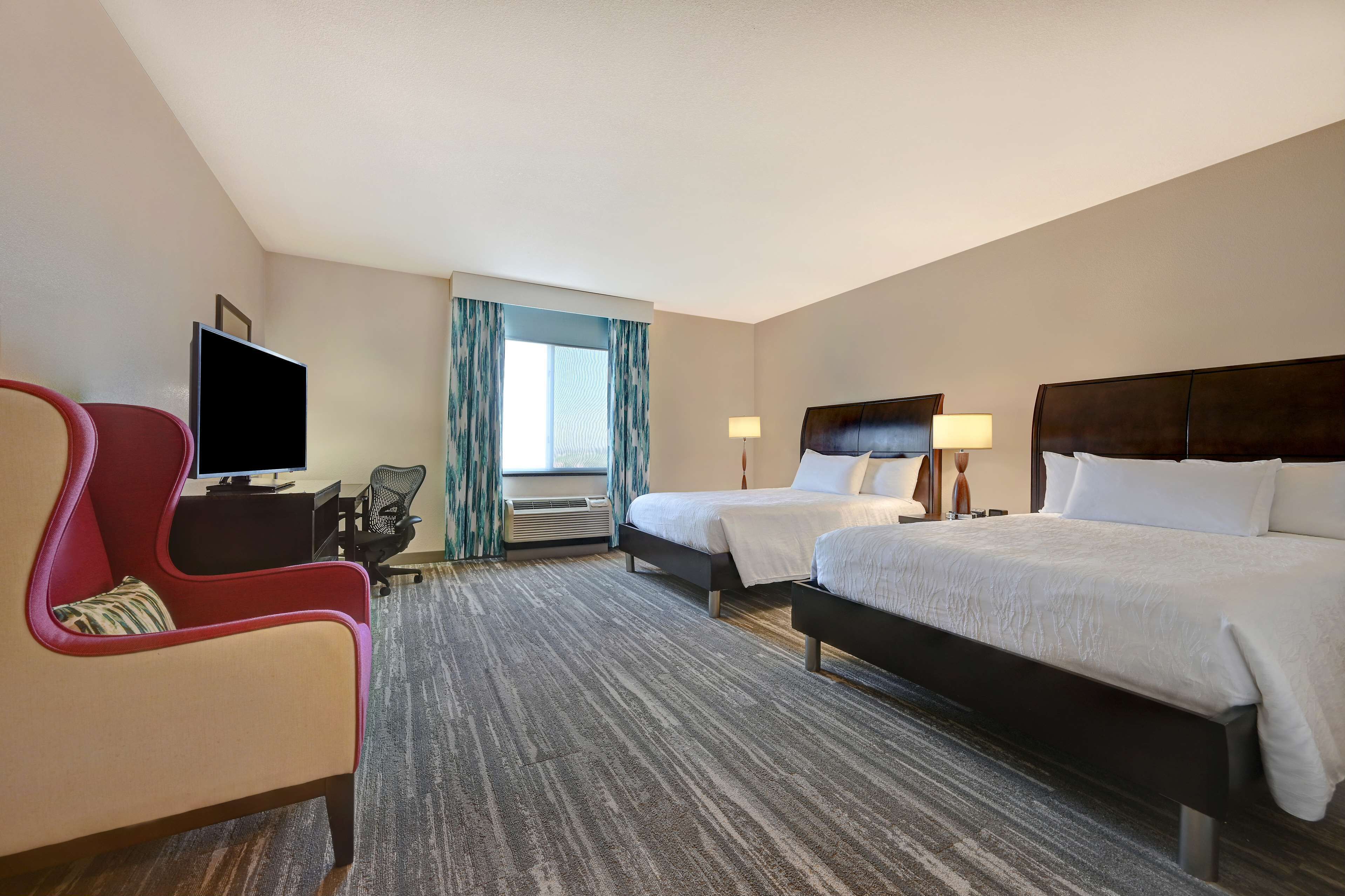 Una habitación de hotel con una cama grande, otra más pequeña, un televisor, un escritorio y una silla.