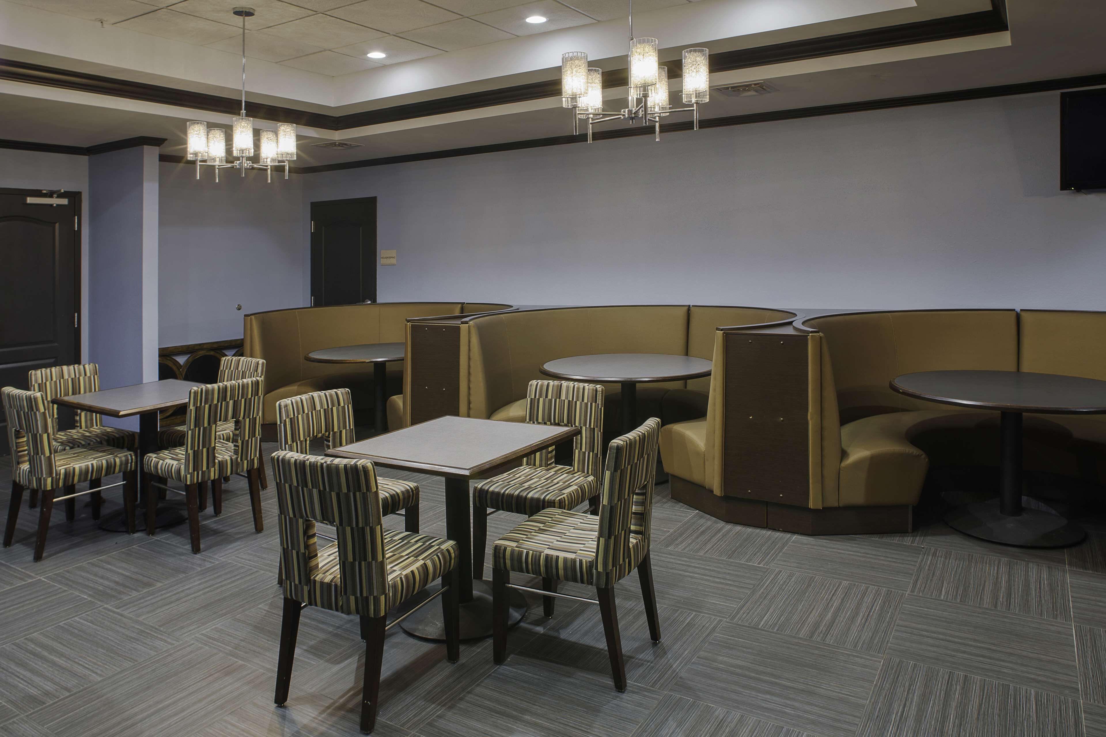 Un comedor de hotel con cabinas y mesas, sillas estampadas y candelabros.