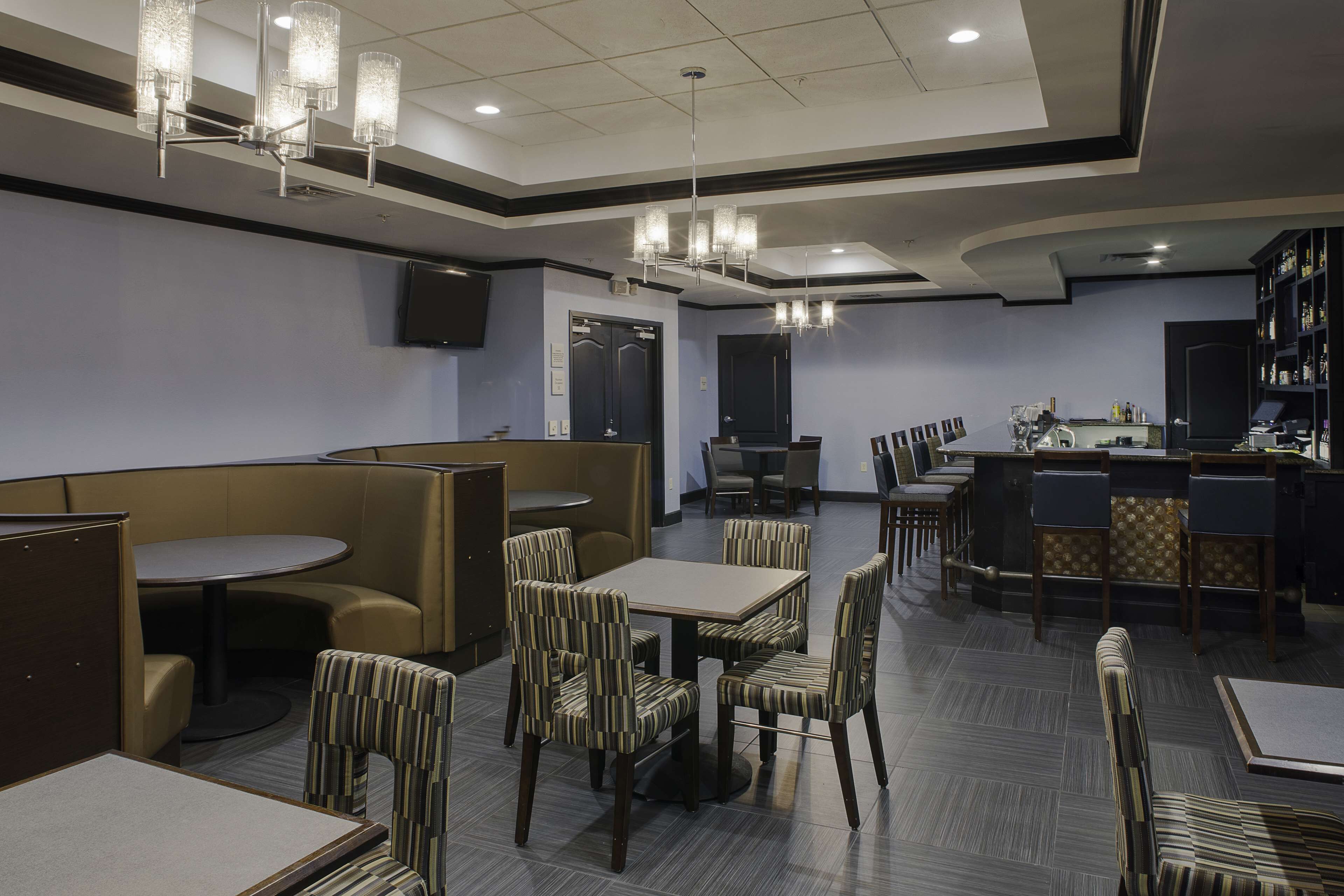 A hotel lobby with seating areas, a bar, and a television screen.