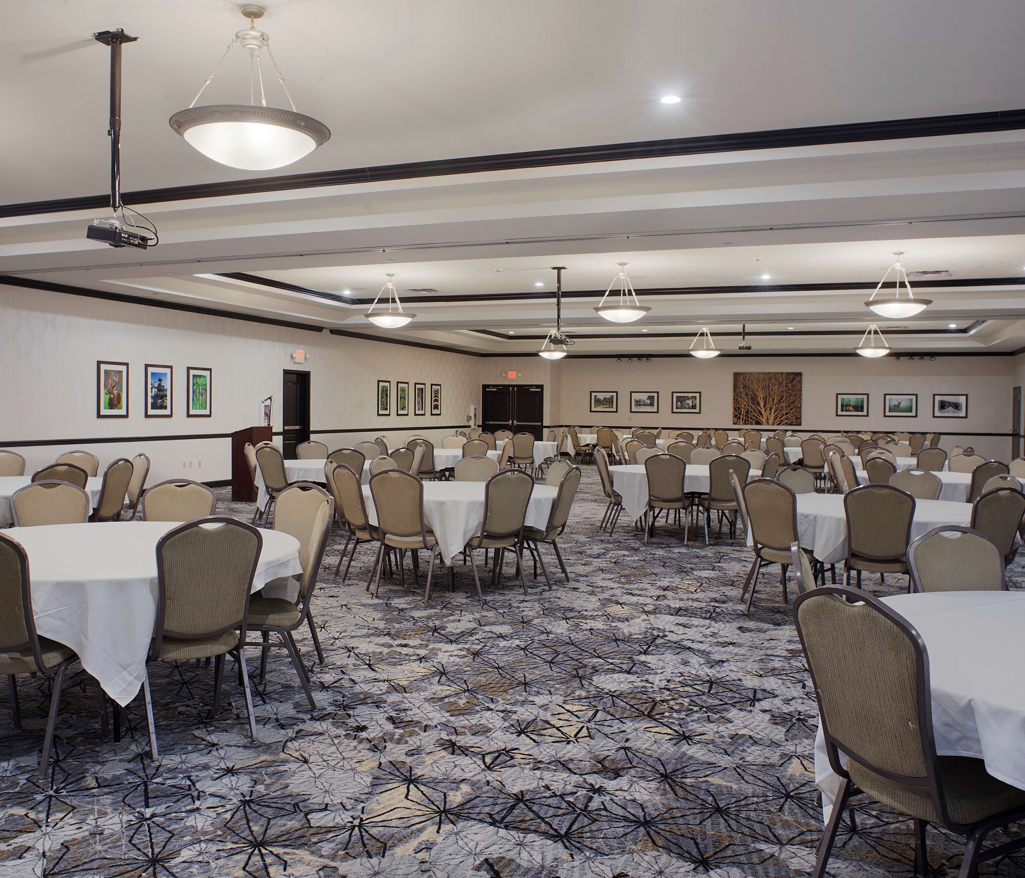A conference room with multiple tables and chairs, a projector, and a podium.
