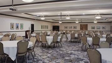 A conference room with multiple tables and chairs, a projector, and a podium.