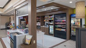 A small shop with a coffee machine, snacks, and a refrigerator stocked with drinks. - Hilton Garden Inn Jonesboro (Jonesboro)