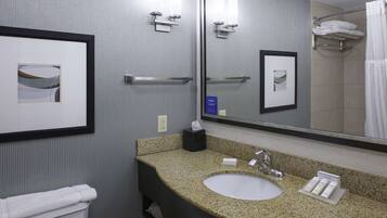 A bathroom with a granite countertop sink, a mirror, framed pictures, and a towel rack with folded towels.