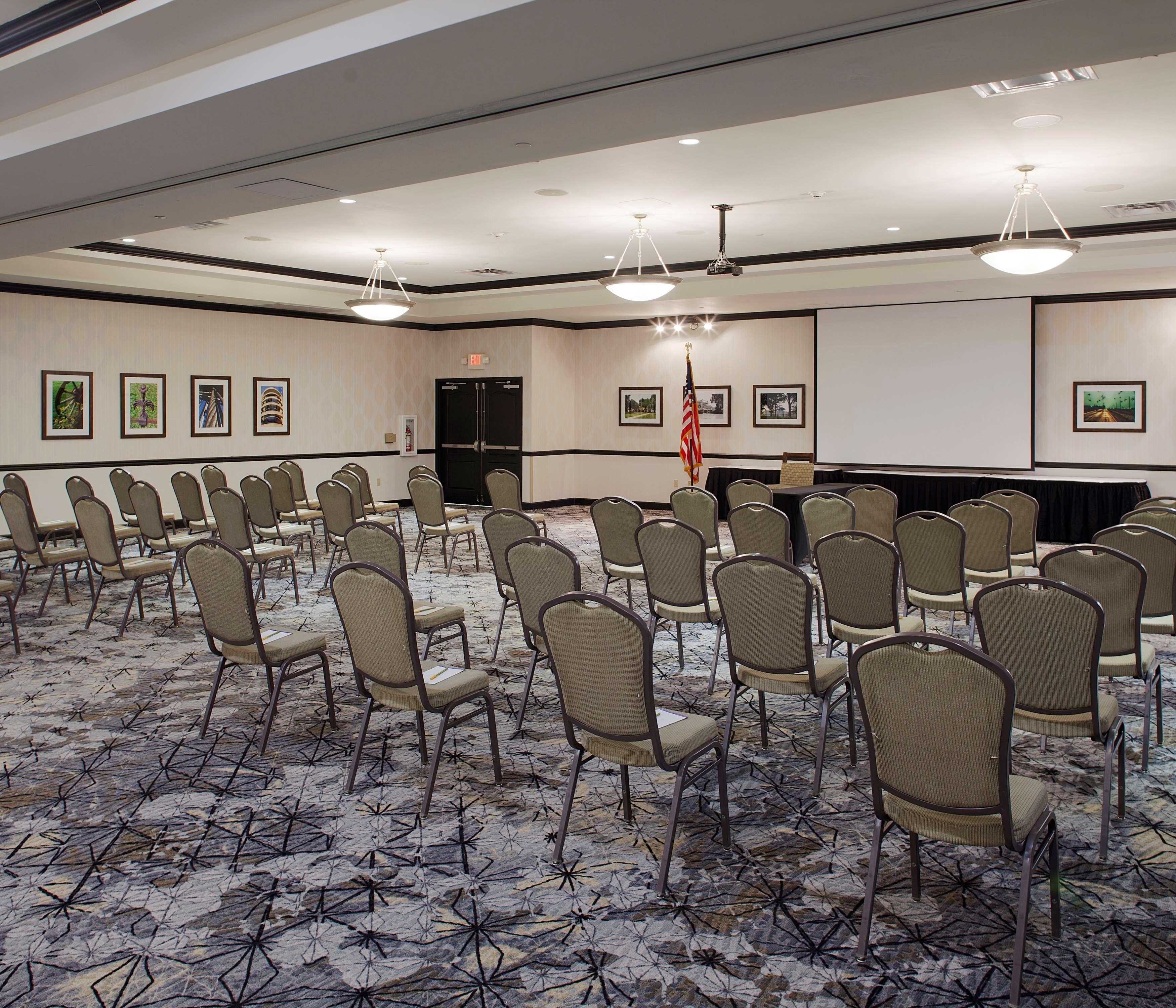 A conference room with rows of chairs, a projector screen, and a podium.