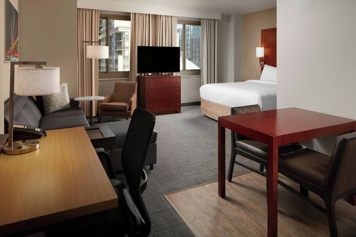 Une chambre d’hôtel avec un lit, un bureau, un canapé, une télévision et une lampe.