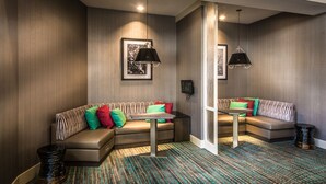 Une chambre d’hôtel moderne avec un canapé d’angle, une petite table et deux lampes suspendues.