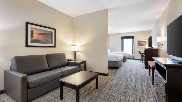 Een hotelkamer met een bank, salontafel, televisie, bureau en bed.