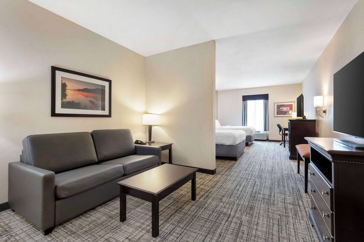 Une chambre d’hôtel équipée d’un canapé, d’une table basse, d’une télévision, d’un bureau et d’un lit.