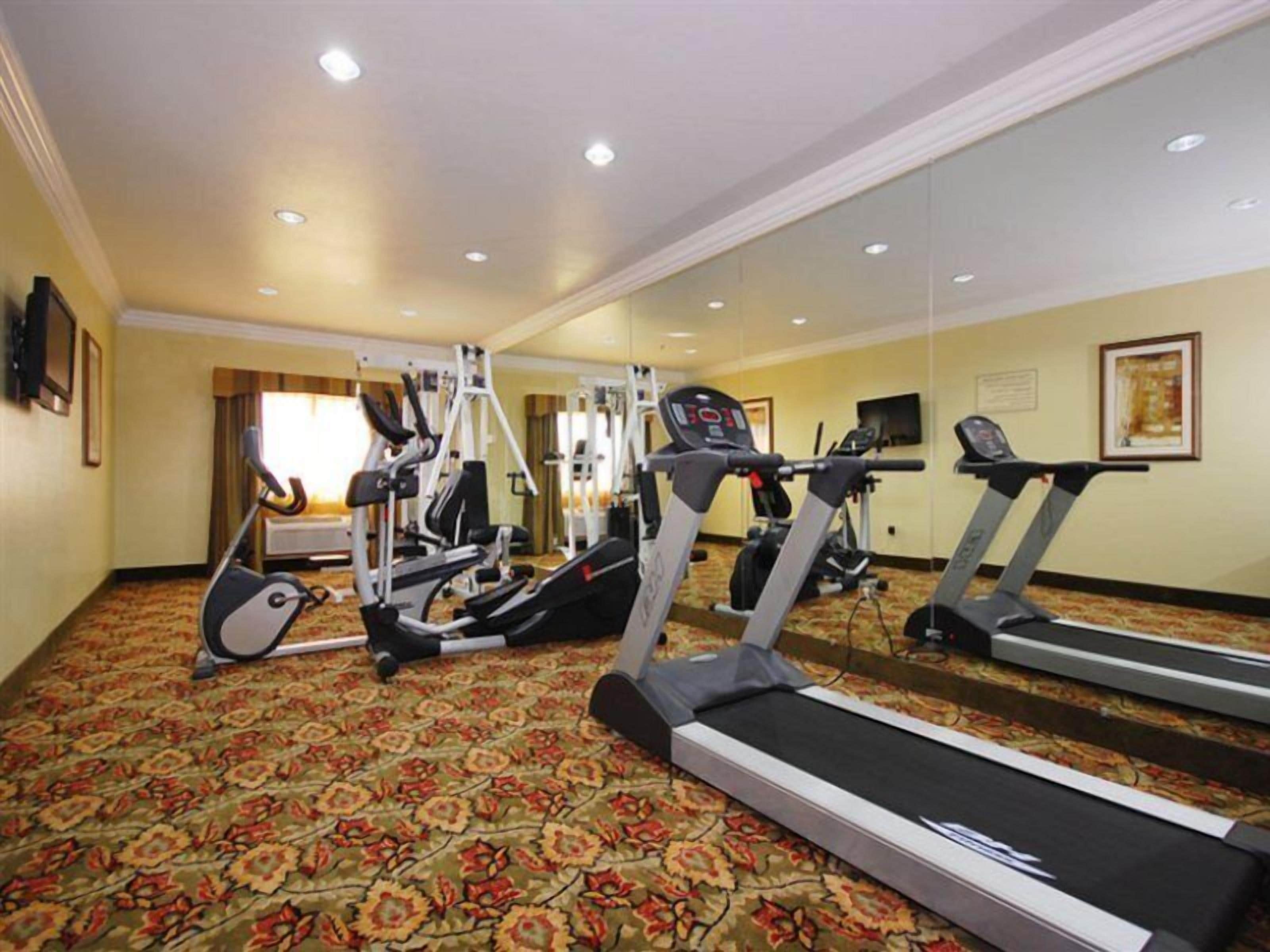 A hotel fitness center with treadmills, elliptical machines, and weight equipment.