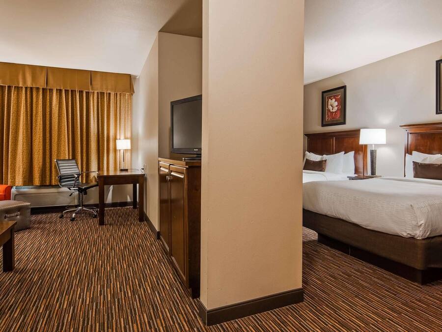 Habitación de hotel con cama, escritorio, silla, televisor y dos cuadros en la pared.