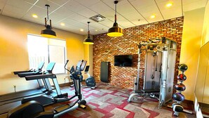 A gym with treadmills, elliptical machines, a weight bench, and a wall-mounted TV. - Radisson Hotel River Falls (River Falls)