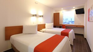 Ett hotellrum med två sängar, en tv som är monterad på väggen och ett fönster med utsikt över staden.