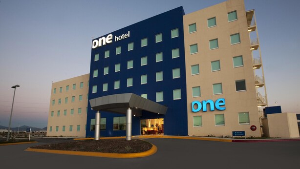 Ett hotell med en tydlig skylt som visar hotellets namn, en modern arkitektonisk design och en väl upplyst entré.