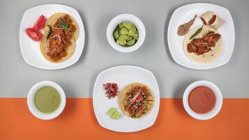 Vista cenital de una mesa con varios platos, incluyendo tacos, un tazón de guacamole y un tazón de salsa.