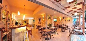 A restaurant with a bar area, multiple seating options including tables and chairs, and a warm interior ambiance.