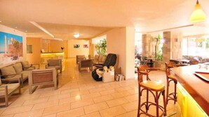 A spacious living area with a sofa set, a dining table with chairs, and a kitchen area in the background. - Carina Hotel Rhodes (Rhodes)