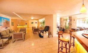 A spacious living area with a sofa set, a dining table with chairs, and a kitchen area in the background. - Carina Hotel Rhodes (Rhodes)