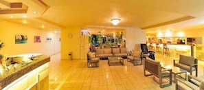 A spacious living area with a sofa set, coffee table, and a bar area with chairs. - Carina Hotel Rhodes (Rhodes)