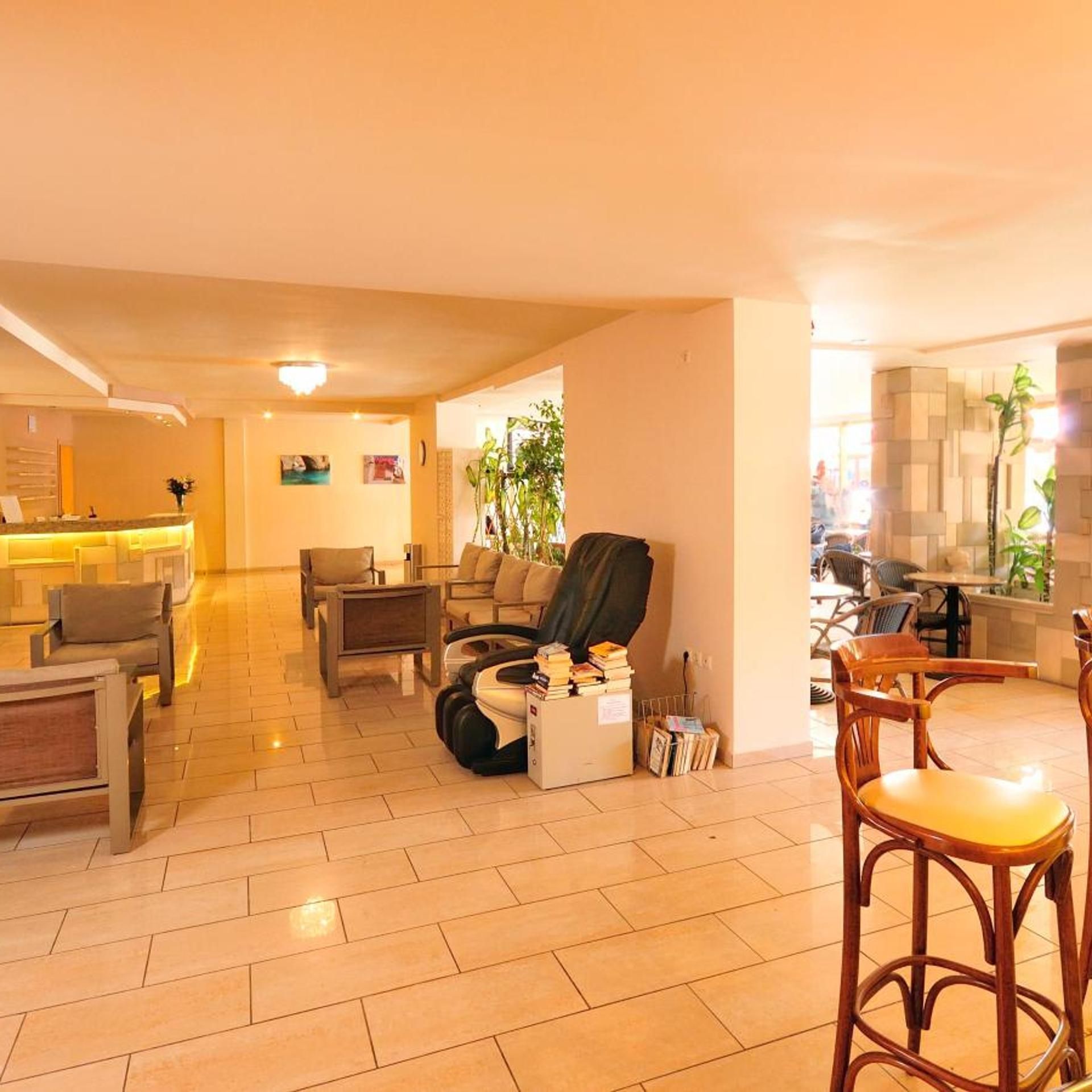 Eine Hotelhalle mit Empfangsschalter, Sitzgelegenheiten und einer Bar.