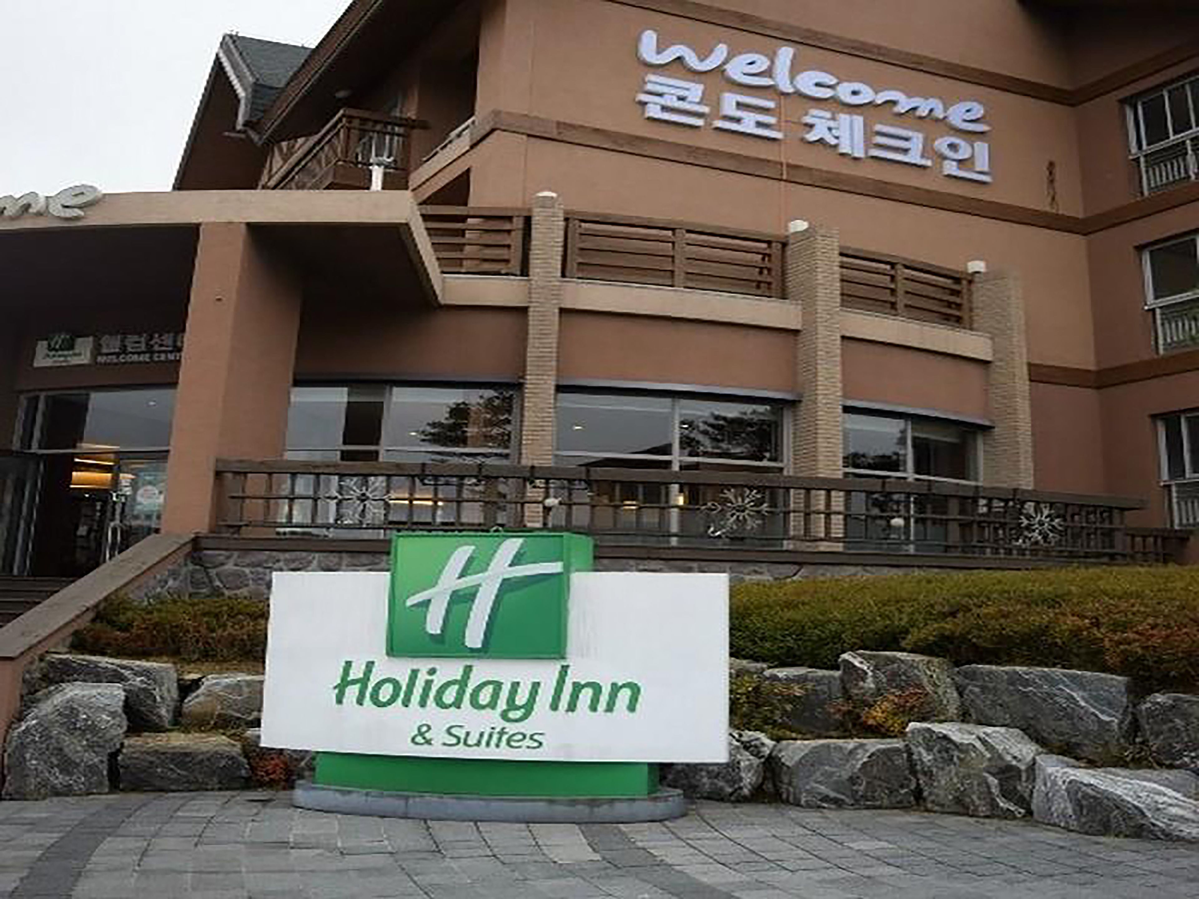 A Holiday Inn & Suites building with a signboard in front.