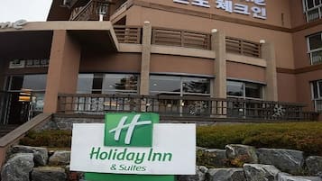 A Holiday Inn & Suites building with a signboard in front.