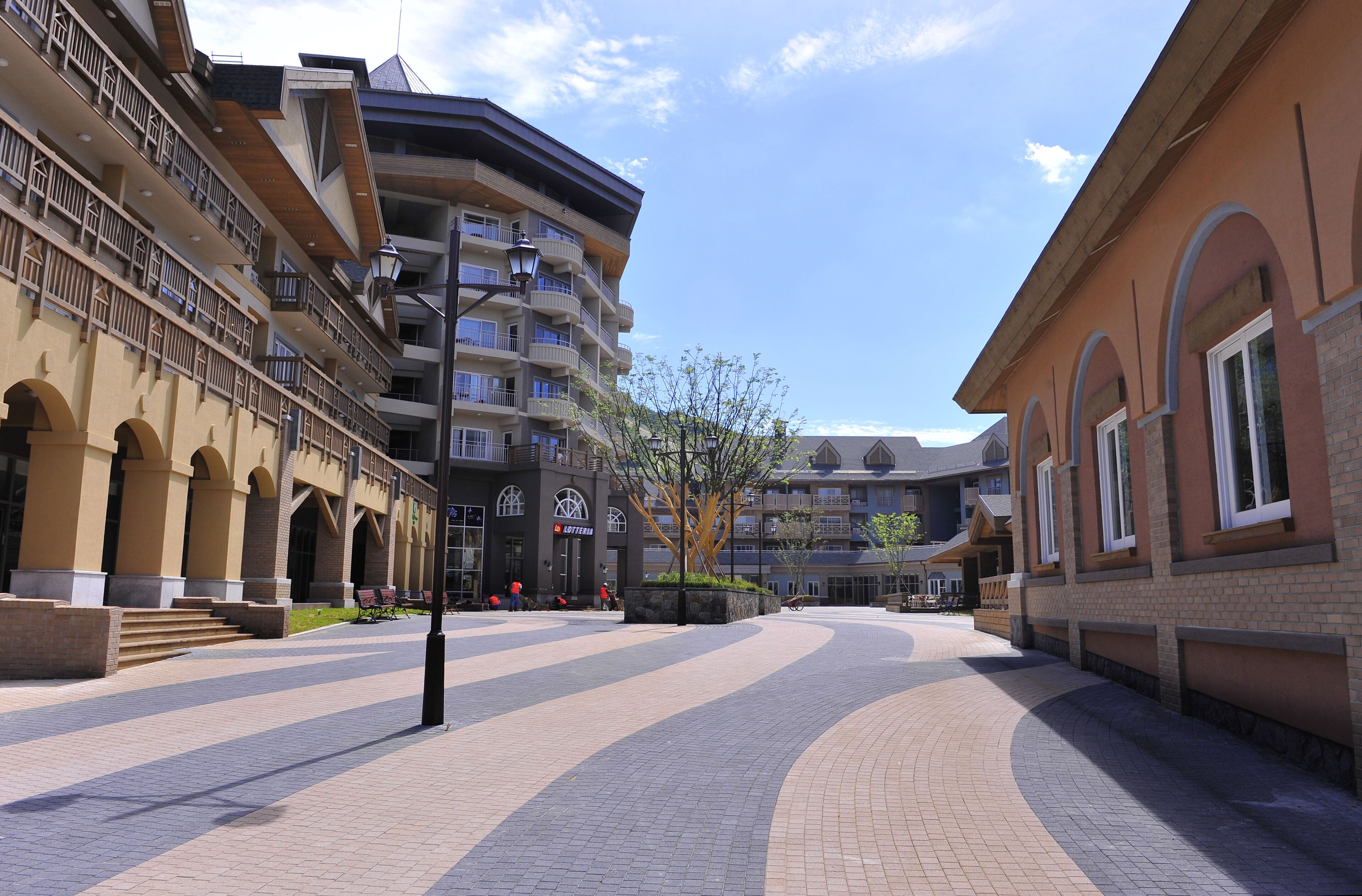 A multi-story hotel with balconies, a central courtyard, and a clear sky.