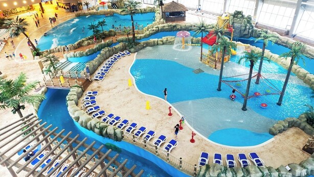 An indoor water park with multiple pools, slides, and a beach area with sun loungers. - Holiday Inn Alpensia Pyeongchang Suites by IHG (Pyeongchang)