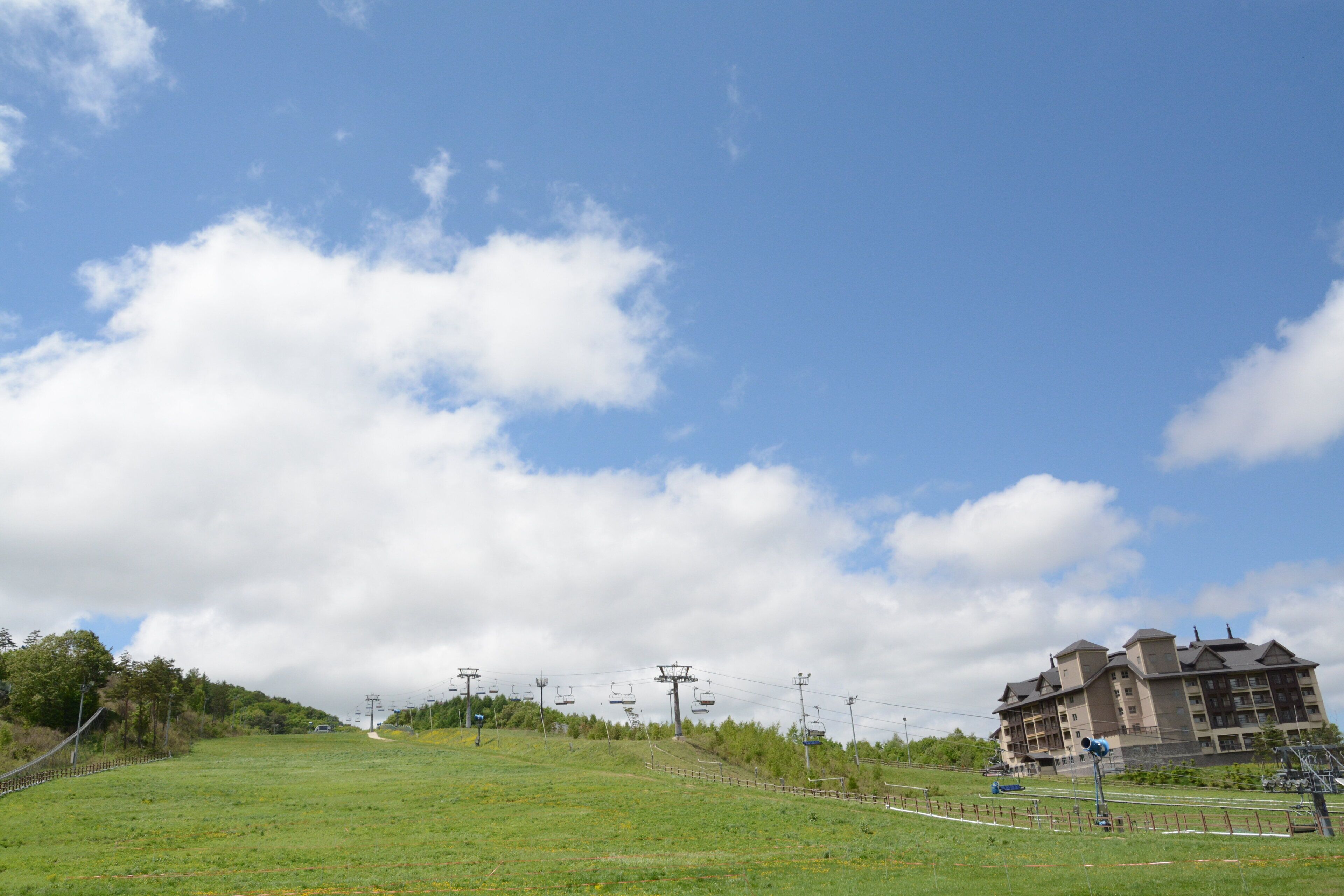 A grassy field with a ski lift and a building in the background.